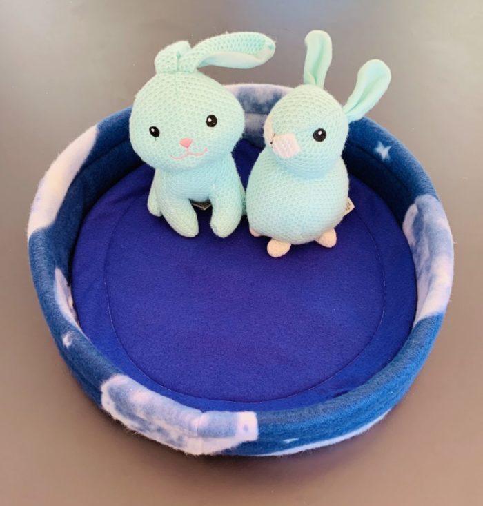 two bunnies round cosy bed